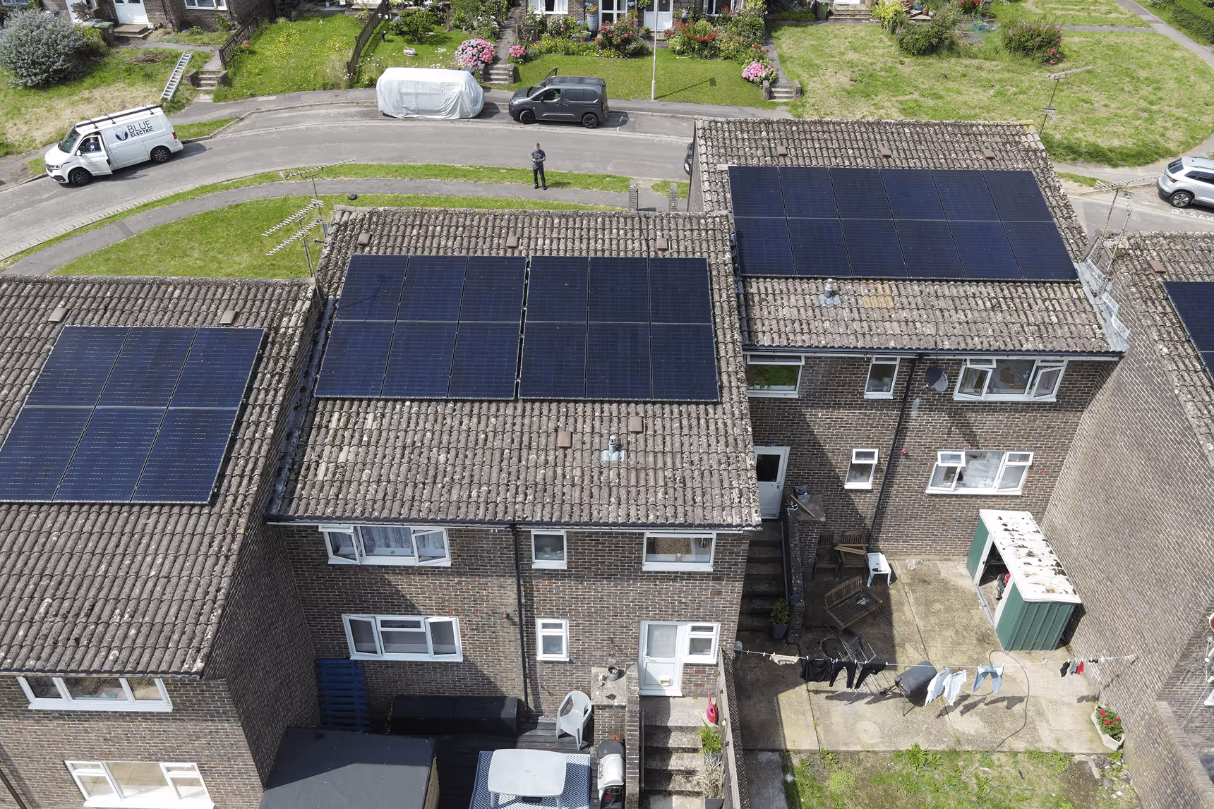 Aerial drone view of terraced houses with solar panels and Blue Electric van on street